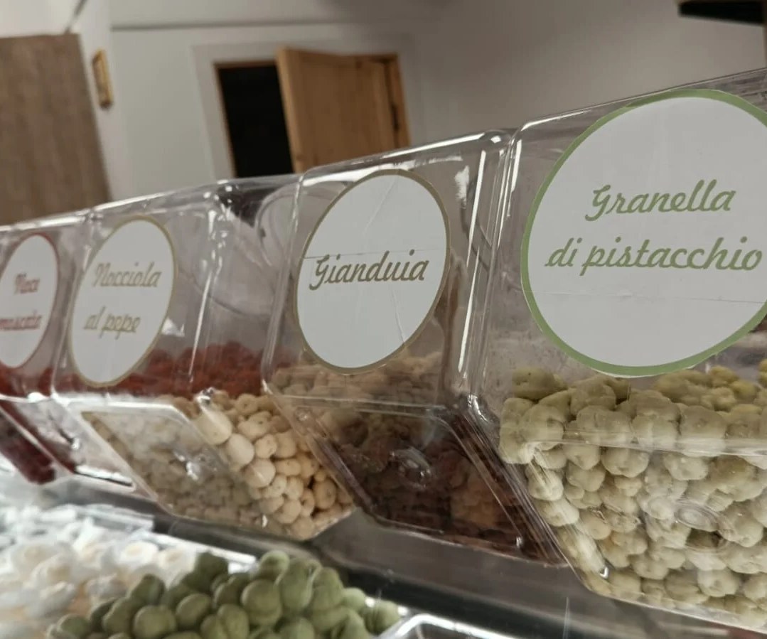 Contenitori con granella di pistacchio, gianduia e nocciola in una cioccolateria a Nuoro